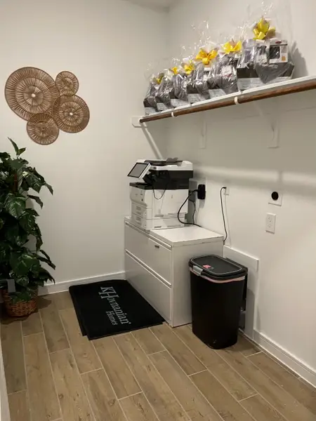 A tidy office nook with wood flooring, a printer, decorative wall art, and a lush plant for a refreshing touch.