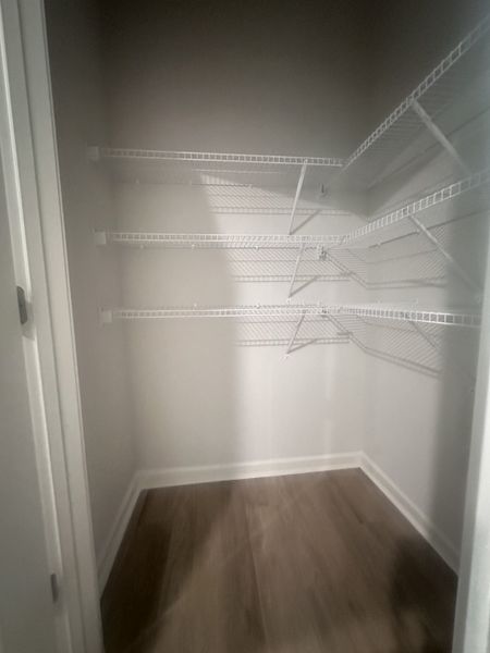 A spacious walk-in closet with sleek wire shelving and wood flooring, perfect for organized storage.