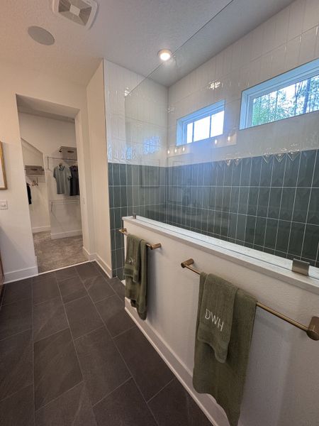 A modern bathroom with sleek dark tiles, half-tiled walls, and elegant brass towel racks.