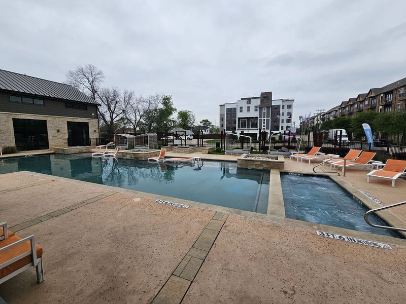 A modern pool area with lounging chairs in SoHo Square by Megatel Homes (Dallas, TX).
