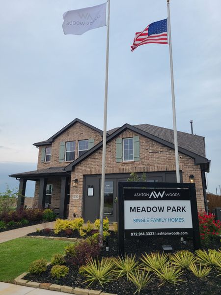 A charming brick home with green shutters and a manicured garden in Meadow Park by Ashton Woods (Melissa, TX).