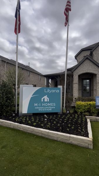 A charming brick home entrance with flags, located in Lilyana by M/I Homes (Prosper, TX).