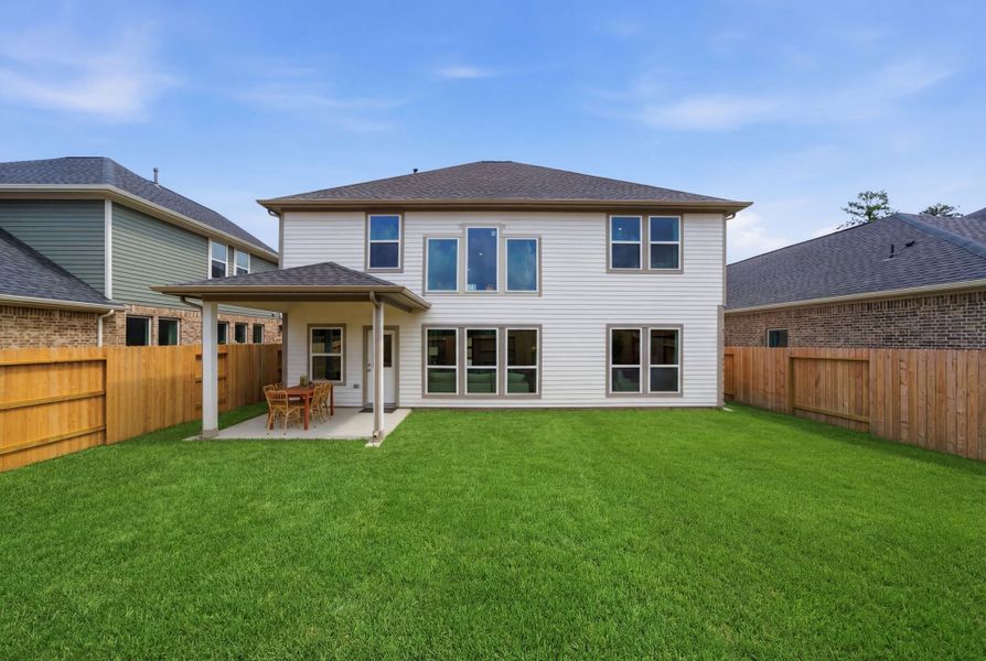 A house with a fence and a lawn in front of it.