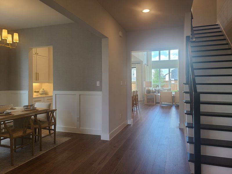 A modern open-concept living space with sleek wood flooring, elegant dining area, and bright natural lighting.