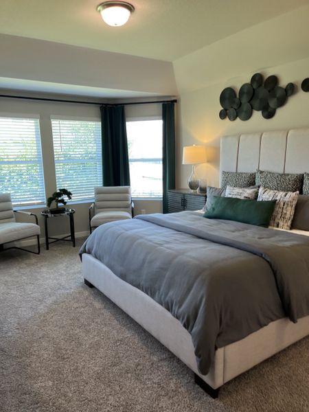 A cozy bedroom featuring a plush bed, elegant seating, and large windows with stylish dark curtains.