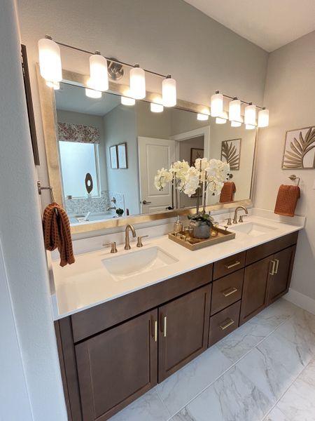 Elegant bathroom with a double vanity, modern lighting, and chic decor accents.