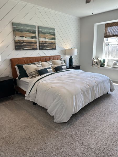 A cozy bedroom with a textured accent wall, plush carpeting, and a comfortable bed adorned with decorative pillows.