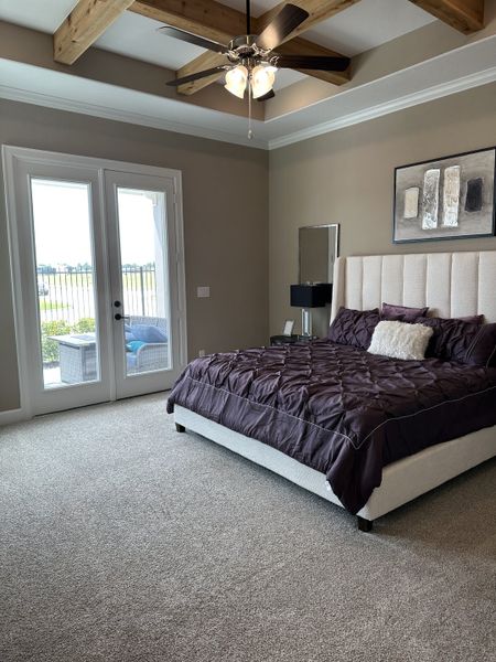 A cozy bedroom featuring a plush bed, beamed ceiling, and French doors opening to a patio view. A cozy bedroom featuring a plush bed, beamed ceiling, and French doors opening to a patio view.
