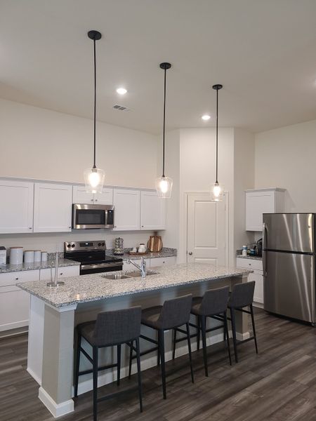 A modern kitchen with sleek granite countertops, stainless steel appliances, and pendant lighting over an island. A modern kitchen with sleek granite countertops, stainless steel appliances, and pendant lighting over an island.