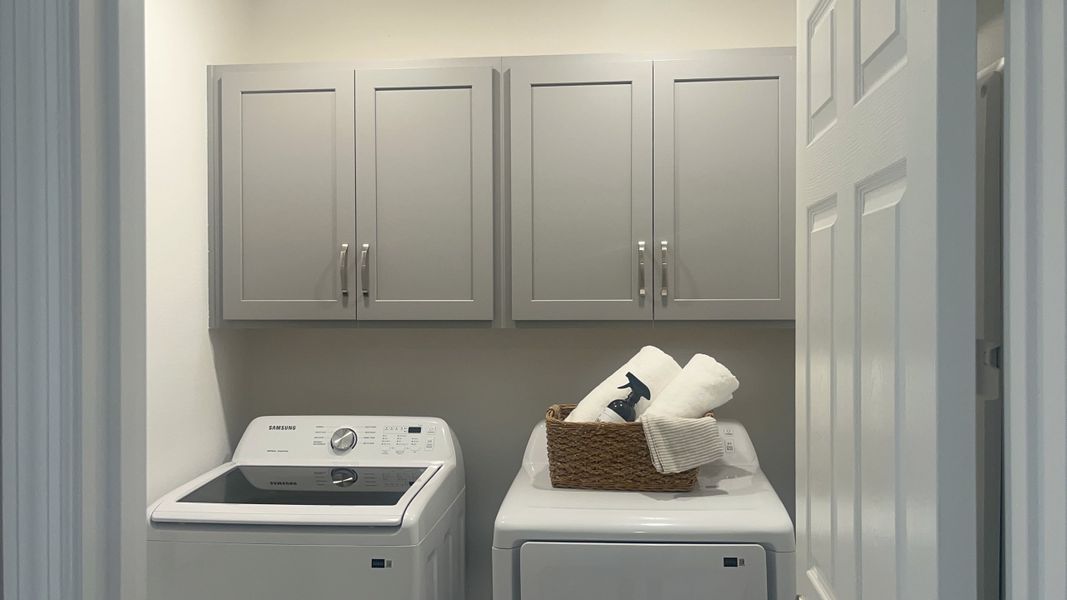 A functional laundry room with sleek gray cabinets, modern appliances, and organized storage solutions.