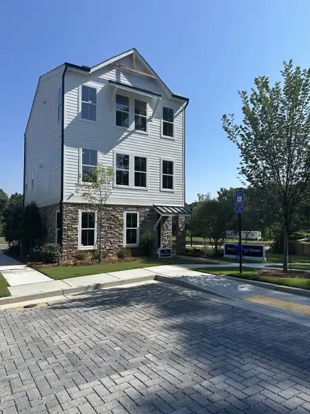 A modern three-story home with stone accents and lush landscaping in Celesta by David Weekley Homes (Decatur, GA).