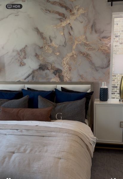 A luxurious bedroom with a marble accent wall, plush pillows, and elegant side table decor. A luxurious bedroom with a marble accent wall, plush pillows, and elegant side table decor.