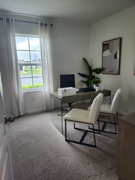 A modern home office with a sleek glass desk, elegant chairs, abstract art, and a large window allowing natural light.
