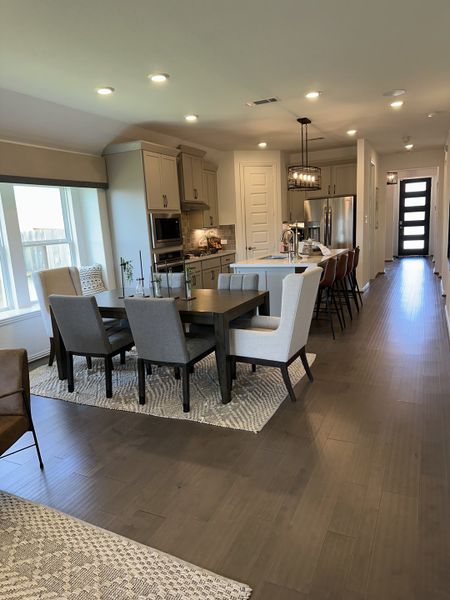 Open-layout dining and kitchen area with sleek cabinetry, modern lighting, and a spacious island for seamless entertaining. Open-layout dining and kitchen area with sleek cabinetry, modern lighting, and a spacious island for seamless entertaining.