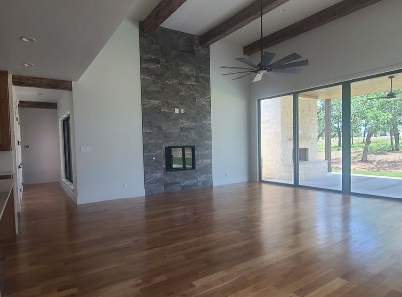 A spacious living area with hardwood floors, a slate tile fireplace, and large sliding glass doors.