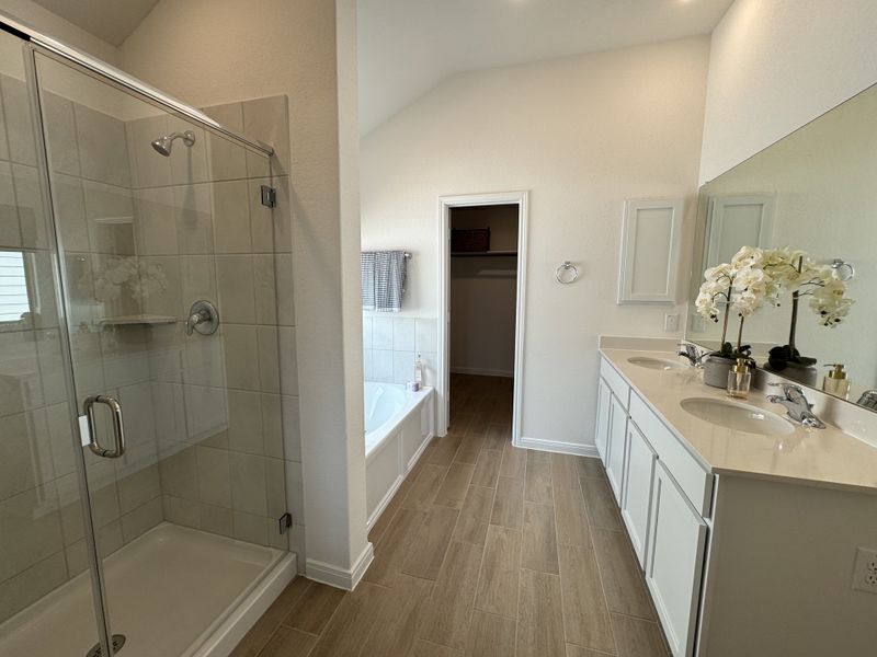 A modern bathroom featuring a spacious glass shower, elegant double vanity, and tub with sleek tile flooring.