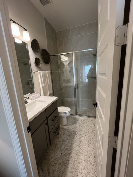 A modern bathroom featuring a glass-enclosed shower, sleek vanity, and pebble-tiled floor.