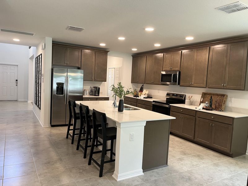 A spacious kitchen with sleek cabinetry, stainless steel appliances, an island, and stylish lighting.