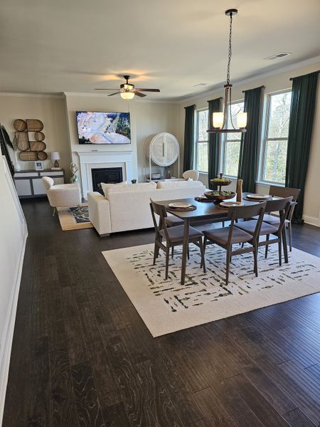 A modern living-dining space with rich wood flooring, cozy seating, and a sleek fireplace, complemented by large windows and stylish decor.