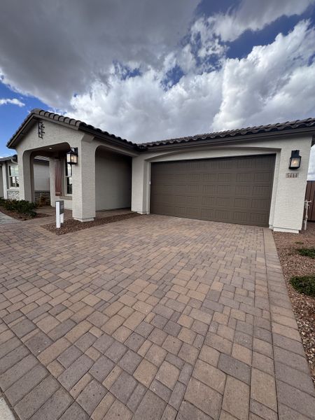 A modern stucco home with a tiled roof and paved driveway in Seasons at Trevino by Richmond American Homes (Glendale, AZ).
