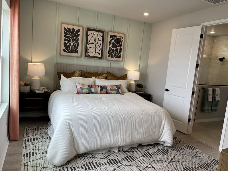 A cozy bedroom with elegant bedding, abstract artwork, and ambient lighting creating a serene atmosphere.