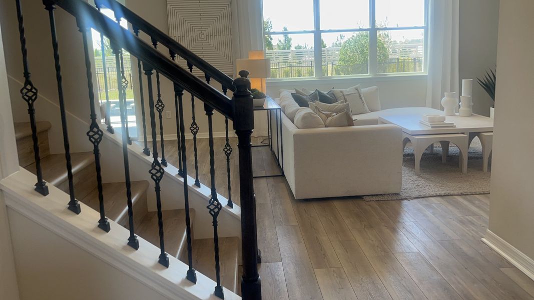 A cozy living area with wooden floors, a plush sofa, and elegant decor, featuring a stylish staircase with wrought iron railings. A cozy living area with wooden floors, a plush sofa, and elegant decor, featuring a stylish staircase with wrought iron railings.