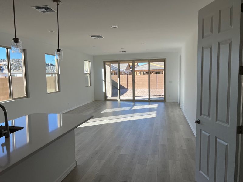 A spacious, sunlit living area with sleek wooden flooring, modern fixtures, and large sliding glass doors to the backyard.