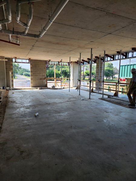 Clear shot of the building under construction, with workers engaged in fitting windows and exterior framing at Congress Lofts Saint Elmo by Intracorp (Austin, TX).