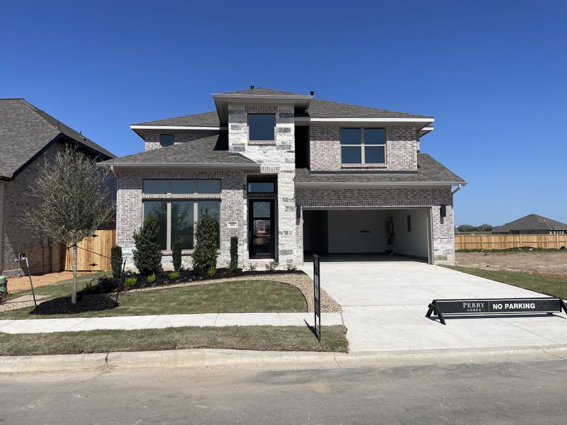 A spacious brick home with modern landscaping in Legacy at Lake Dunlap 50' by Perry Homes, New Braunfels, TX.
