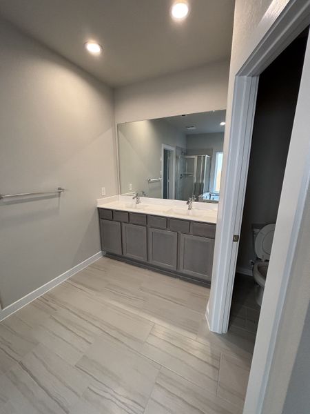 A modern bathroom featuring a sleek double vanity, expansive mirror, and stylish gray tile flooring.