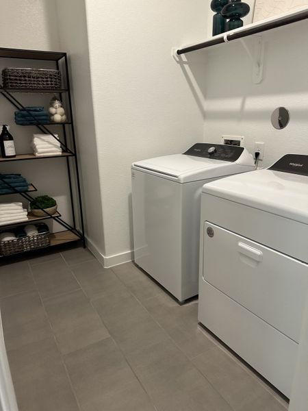 A modern laundry room featuring sleek appliances, open shelving, and neutral tile flooring for efficient functionality. A modern laundry room featuring sleek appliances, open shelving, and neutral tile flooring for efficient functionality.