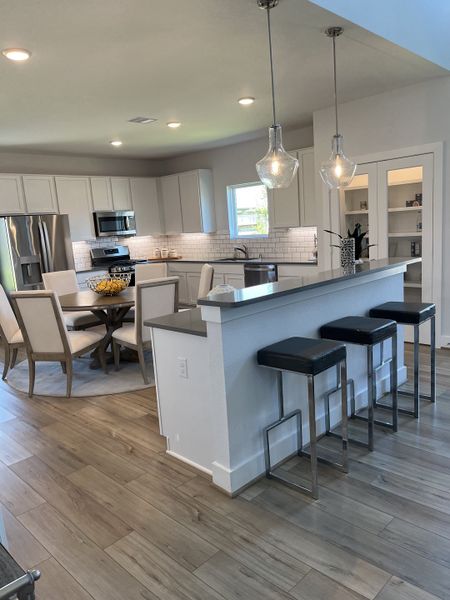 A modern kitchen with stainless appliances, pendant lighting, and a chic breakfast bar featuring sleek barstools.