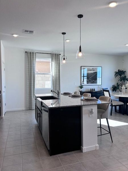A modern kitchen with a sleek island, pendant lighting, and a dining area with elegant decor. A modern kitchen with a sleek island, pendant lighting, and a dining area with elegant decor.