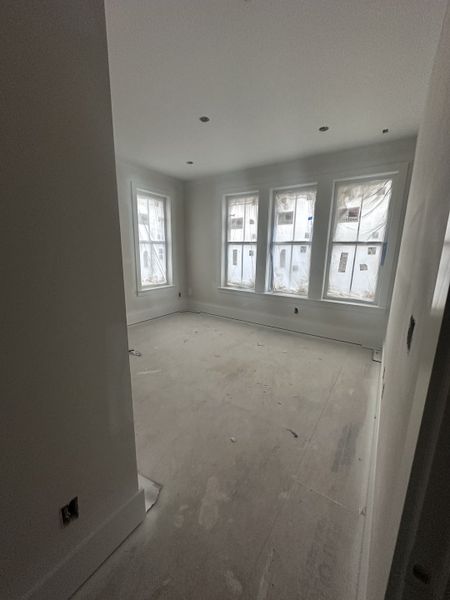 A bright, unfinished room with large windows, white walls, and a clean, spacious layout.