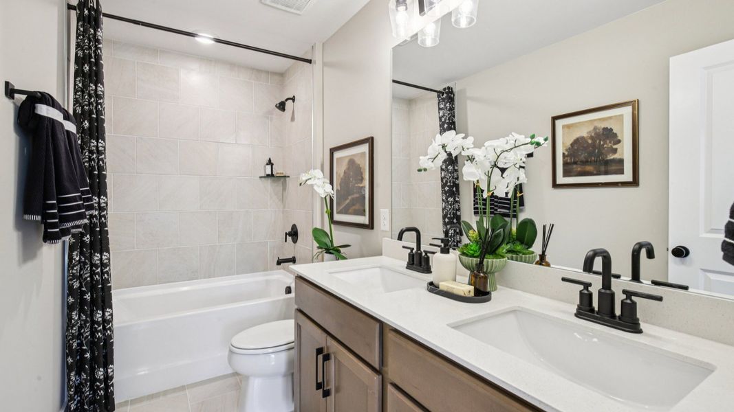 Double sink vanity, toilet, and shower located between secondary bedrooms