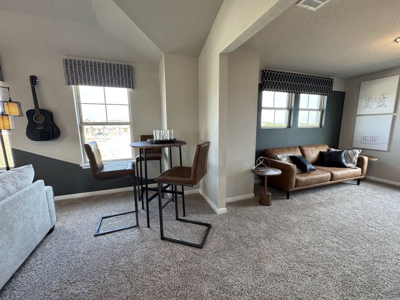 A cozy entertainment room with a leather sofa, high-top table, and guitar wall decor creating a relaxed atmosphere.