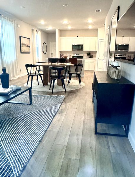 A modern open-concept living area with sleek wood flooring, a round dining table, and elegant decor.