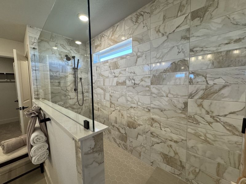 A luxurious shower with marble-tiled walls, glass enclosure, and sleek fixtures for a modern touch.