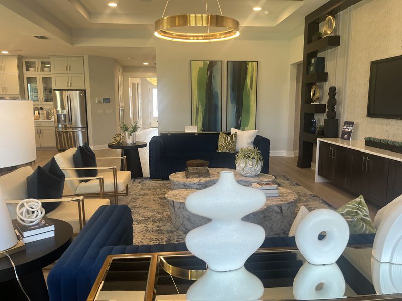 A chic living area with plush seating, abstract art, and modern decor, featuring a sleek kitchen in view. A chic living area with plush seating, abstract art, and modern decor, featuring a sleek kitchen in view.