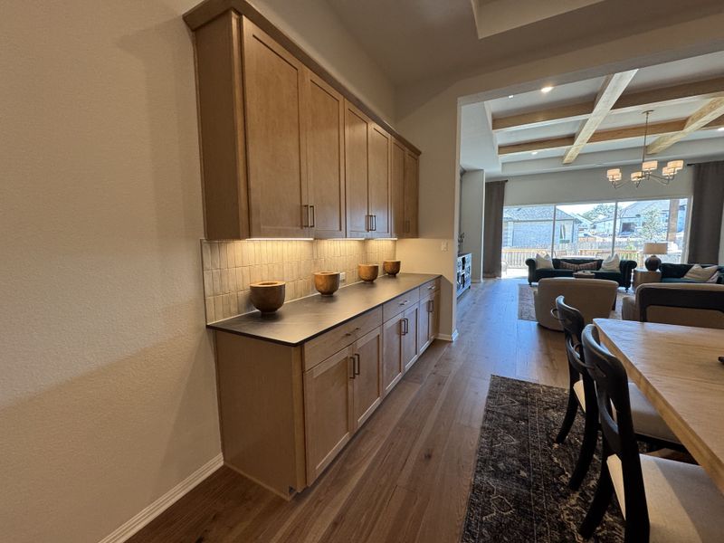 A cozy dining area with warm wood cabinetry and open living space featuring elegant furnishings and natural light.