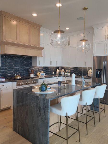 A modern kitchen with a sleek island, elegant pendant lights, and blue hexagon backsplash. A modern kitchen with a sleek island, elegant pendant lights, and blue hexagon backsplash.