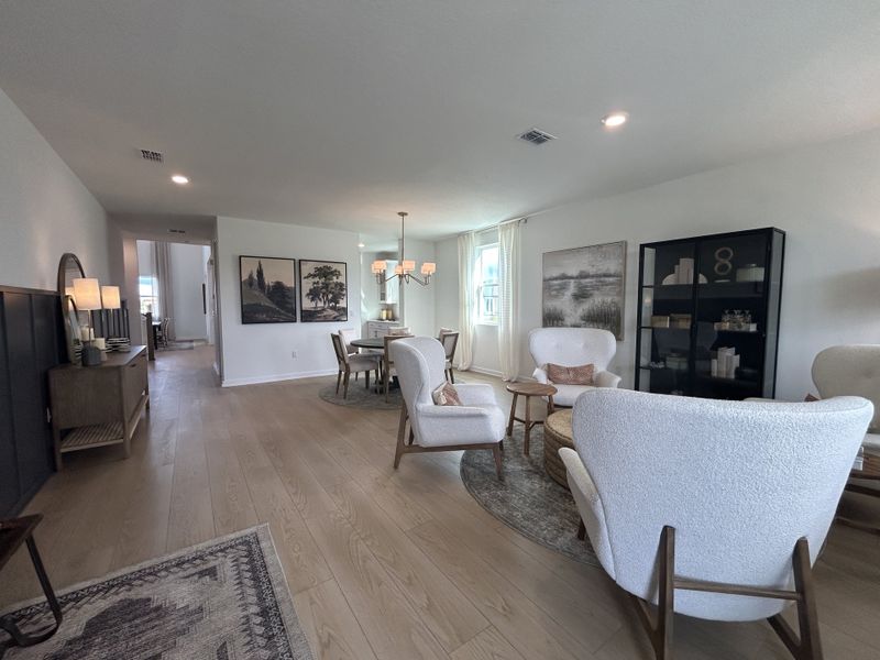 A spacious living and dining area with light wood flooring, cozy seating, and elegant decor.