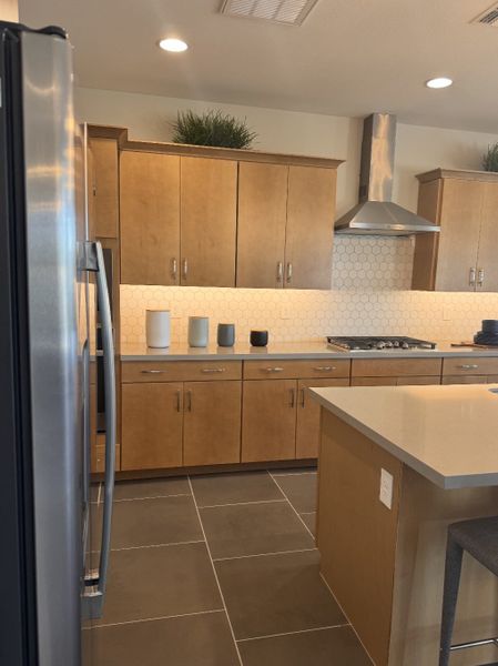 A modern kitchen with light wood cabinets, hexagonal backsplash, and sleek stainless steel appliances. A modern kitchen with light wood cabinets, hexagonal backsplash, and sleek stainless steel appliances.