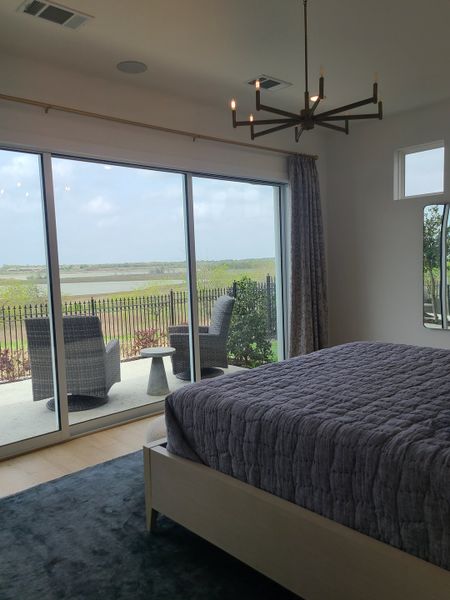 A serene bedroom with a cozy bed, modern chandelier, and glass doors opening to a patio with scenic views. A serene bedroom with a cozy bed, modern chandelier, and glass doors opening to a patio with scenic views.
