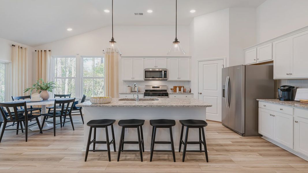 Open kitchen Avondale model in Bluffs at Sun Colony in by DRB homes offering light wood floors and high ceilings