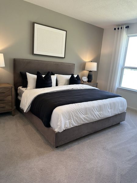 A cozy bedroom with a plush gray bed, elegant decor, and soft lighting, perfect for relaxation.