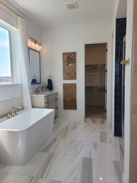 A luxurious bathroom featuring a freestanding tub, marble flooring, elegant fixtures, and chic wall decor.