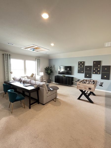 A cozy living room featuring a plush sofa, elegant decor, foosball table, and ample natural light.