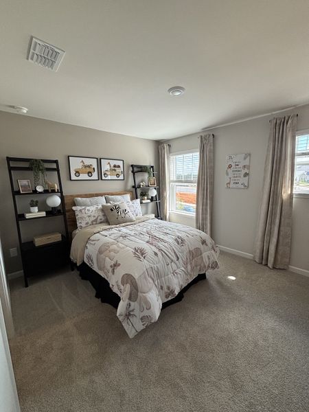 A cozy bedroom featuring a patterned comforter, natural light, and modern shelving.