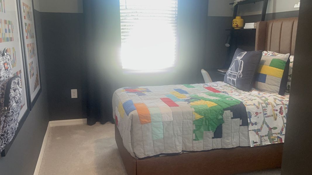 A cozy bedroom with dark walls, colorful bedding, and playful LEGO-themed decor.